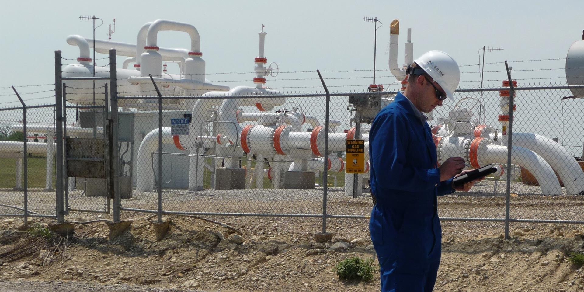 Engineer working on his tablet next to chemical facility